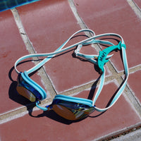 Sea foam green dolphin shaped Swim Loops goggle tag to label swim goggles attached to swim goggles next to swimming pool