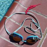 Dark pink alligator shaped Swim Loops goggle tag to label swim goggles attached to swim goggles next to swimming pool