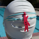 Dark pink alligator shaped Swim Loops goggle tag with name written on it attached to swim goggles on swimmer's head. Make sure everyone knows those are your swim goggles. Get your Swim Loops goggle tags at www.swimloops.com.