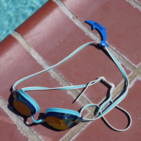 Blue dolphin shaped Swim Loops goggle tag to label swim goggles attached to swim goggles next to swimming pool