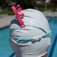 Dark pink Drowning Daryl shaped Swim Loops goggle tag for labeling swim goggles attached to swim goggles on swimmers head