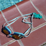 Sea foam green octopus shaped Swim Loops goggle tag to label swim goggles with name written on it attached to swim goggles next to pool